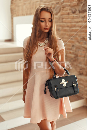 Beautiful elegant woman in a pink dress with a bag 49437603