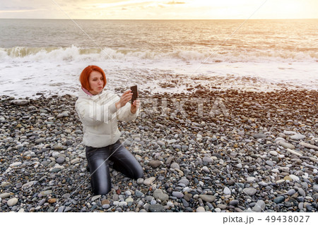 Young woman sits on her lap on shingly shore Young woman sits on her lap on shingly shore 49438027