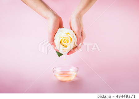 Female hands holding fresh rose flower with oil 49449371