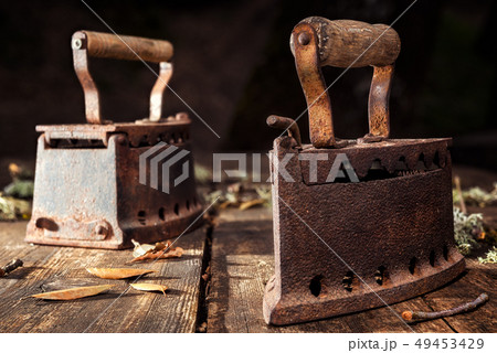 Old rusty iron on a rustic wooden table. Ironing. Old rusty iron on a rustic wooden table. Ironing. 49453429