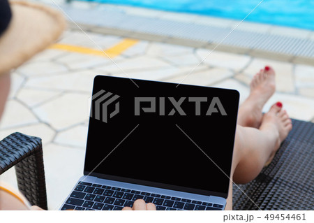 Young woman using laptop near a swimming pool Young woman using laptop near a swimming pool 49454461