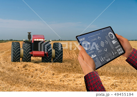Farmer controls an autonomous tractor Farmer controls an autonomous tractor 49455194