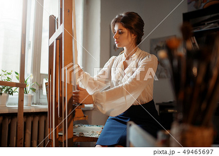 Female artist works at the easel in studio 49465697