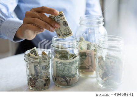 Hand of woman putting money in jar Hand of woman putting money in jar 49469341
