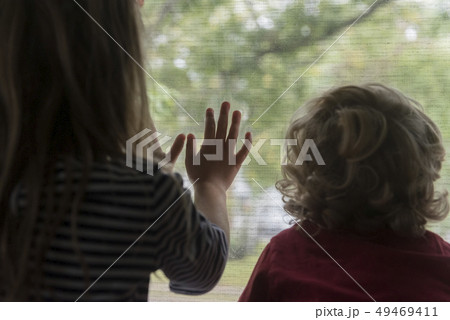 Rear view of children looking out window 49469411