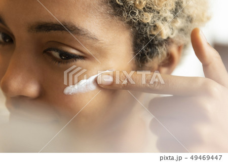 Young woman applying moisturizer Young woman applying moisturizer 49469447