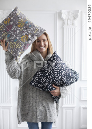 Smiling woman holding patterned cushions Smiling woman holding patterned cushions 49470086