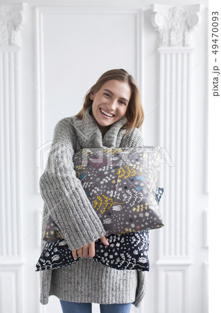 Smiling woman holding patterned cushions 49470093