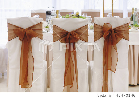 Ribbon tied to dining chairs at wedding 49470146