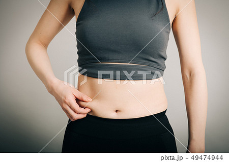 お腹のぜい肉をつまむ若い日本人女性 ダイエットイメージ お腹のぜい肉をつまむ若い日本人女性 ダイエットイメージ 49474944