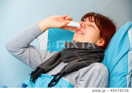 Photo of sick woman using nasal spray lying on bed Photo of sick woman using nasal spray lying on bed 49478236