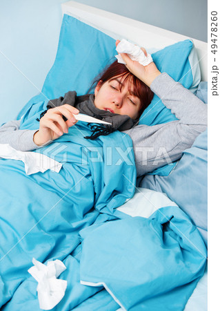 Image of sick woman with thermometer lying on bed. Image of sick woman with thermometer lying on bed. 49478260