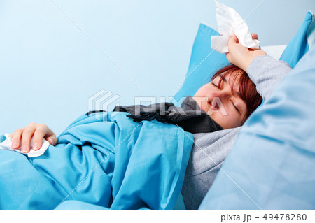 Photo of sick woman with paper handkerchiefs lying on bed 49478280