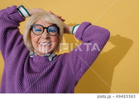 Waist up of Caucasian elderly woman in purple sweater stretching herself indoors Waist up of Caucasian elderly woman in purple sweater stretching herself indoors 49483363