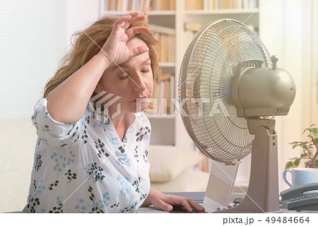 Woman suffers from heat in the office or at home Woman suffers from heat in the office or at home 49484664