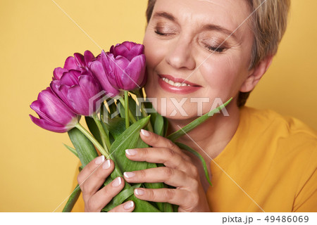 Portrait of charming happy woman with purple tulips in arms Portrait of charming happy woman with purple tulips in arms 49486069