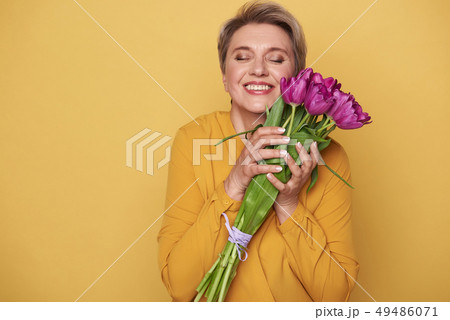 Portrait of charming woman with cute bouquet of purple tulips in arms 49486071