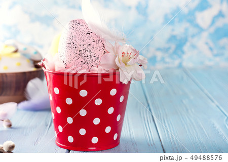 Easter basket (bucket) like nest with cute pink egg and flowers on blue wooden background. Copy 49488576