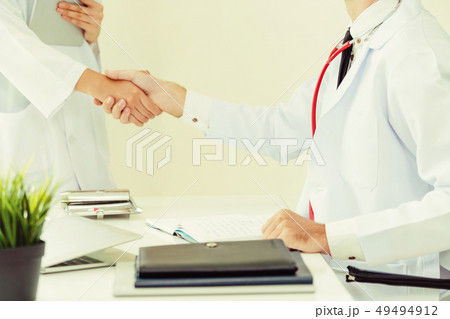 Doctor at hospital shakes hand with another doctor Doctor at hospital shakes hand with another doctor 49494912