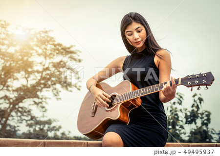 Happy woman plays guitar with nature background. Happy woman plays guitar with nature background. 49495937