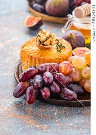 Cheese plate served with grapes, jam, figs, crackers and nuts on a background. 49504341