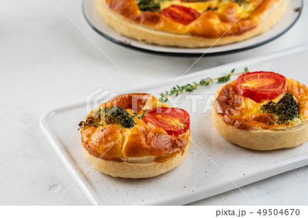 Vegetable pie quiche with broccoli, tomatoes and soft cheese on white background. 49504670