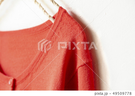 ハンガーにかけたオレンジニットカーディガンの上半身　肩など 49509778