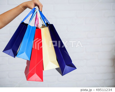 Shopping. Closeup of woman holding color paper shopping bag on white wall background 49511234