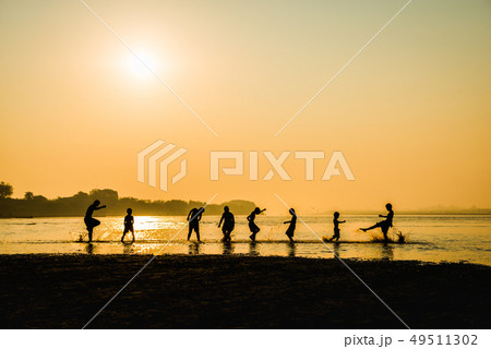 Silhouette of children playing water with friend Silhouette of children playing water with friend 49511302