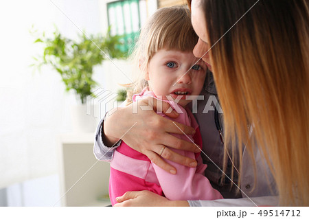 Doctor hugging scared crying little baby girl visiting her office 49514712