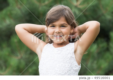 Smiling tanned little girl with both hands in hair 49516001