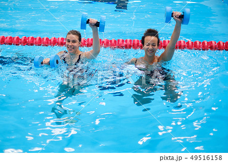 Multiracial couple attending water aerobics class in a swimming pool Multiracial couple attending water aerobics class in a swimming pool 49516158