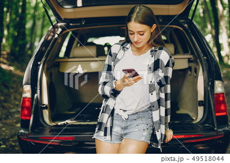 Girl in a summer park near car 49518044