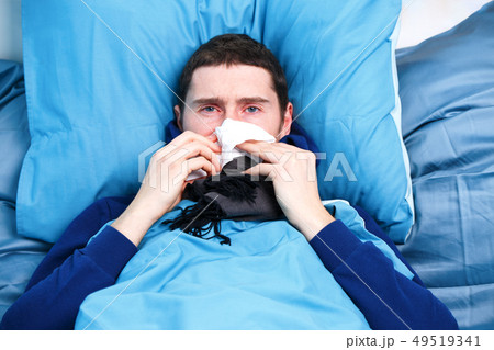 Photo of sick man with handkerchief sitting in bed 49519341
