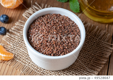 Flax seeds in a bowl, with flax seed oil in the 49528687