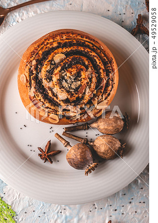 Sweet rolled bun with poppy on white plate with 49529058