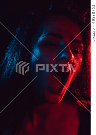 Sensual portrait of a screaming girl behind glass with raindrops 49530753