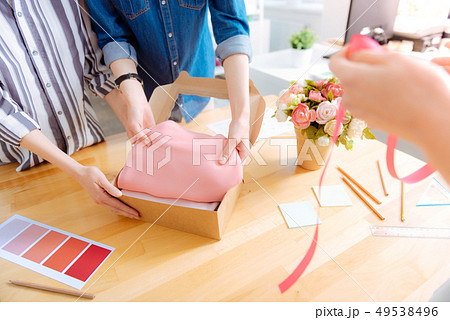 Competent tailor putting pink cloth into box 49538496