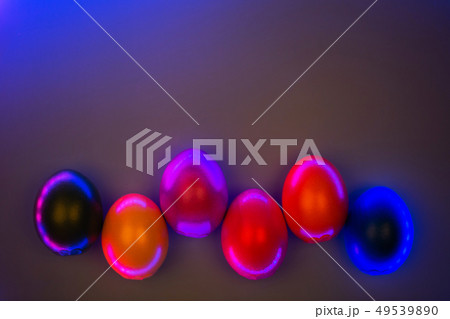 Creative photo of colorful eggs in neon lights on grey background. 49539890