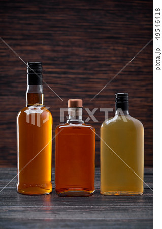 Bottles of whiskey on a  black wooden background. 49546418