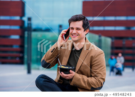 Young businessman with salad and mobile phone at urban city outdoor. Young businessman with salad and mobile phone at urban city outdoor. 49548243
