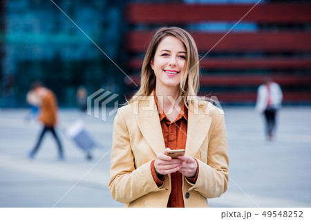businesswoman typing message by phone on the city square 49548252