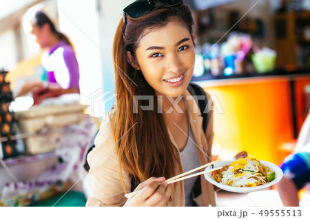 Young female tourist eating pad thai noodle at the shop 49555513