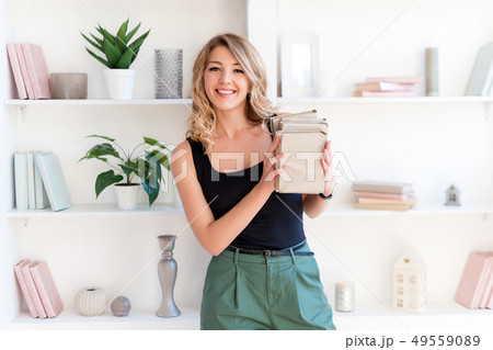 Female student holding books. Beautiful blonde girl keeps a stack of books and smiling. The concept Female student holding books. Beautiful blonde girl keeps a stack of books and smiling. The concept 49559089