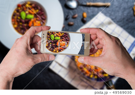 Man taking photo of Chili corn carne on stone Man taking photo of Chili corn carne on stone 49569030