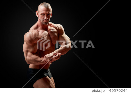 Athletic man posing. Photo of man with perfect physique on black background. Strength and motivation Athletic man posing. Photo of man with perfect physique on black background. Strength and motivation 49570244