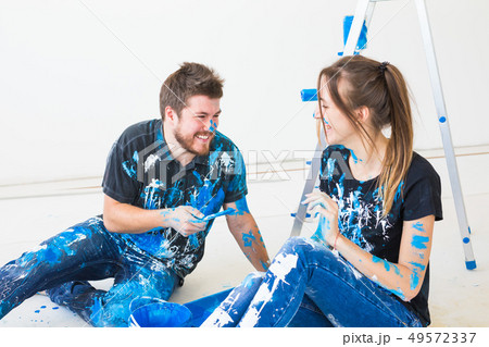 People, redecoration and relationship concept - Young funny couple doing renovation in new apartment 49572337