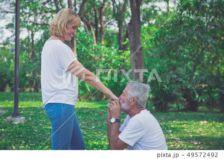 Happy old man kiss his wife hand at the park Happy old man kiss his wife hand at the park 49572492