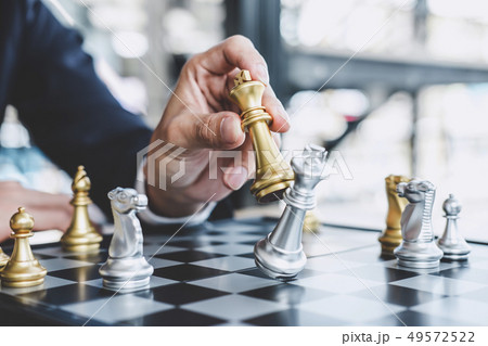 Businessman playing chess game reaching to plan strategy for suc Businessman playing chess game reaching to plan strategy for suc 49572522