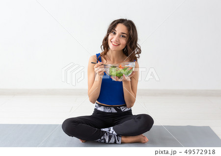 Healthy lifestyle, people and sport concept - Yoga woman with a bowl of vegetable salad after 49572918